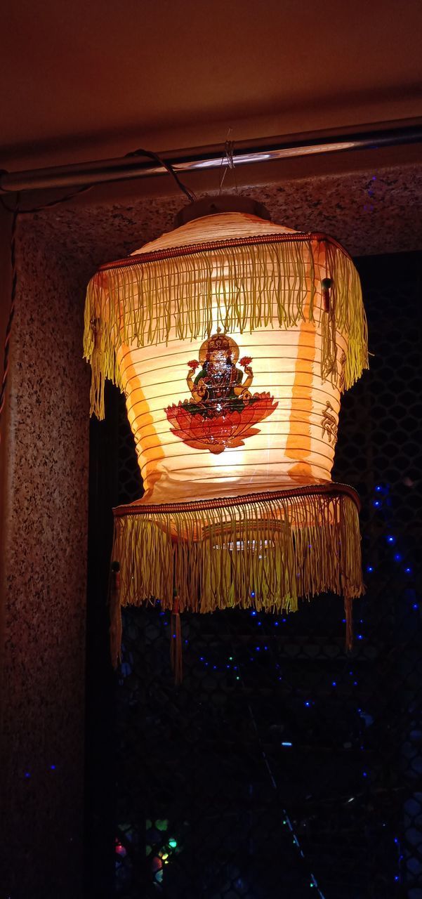 LOW ANGLE VIEW OF ILLUMINATED ELECTRIC LAMP HANGING ON CEILING IN BUILDING