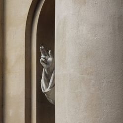 Close-up of hand holding statue against wall