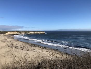 Scenic view of beach against clear blue sky