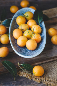 High angle view of plums in plate with burlap on wooden table