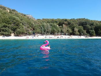 Person floating on water against clear blue sky