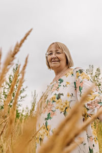 An elderly woman in the tall grass with spikelets. autumn.