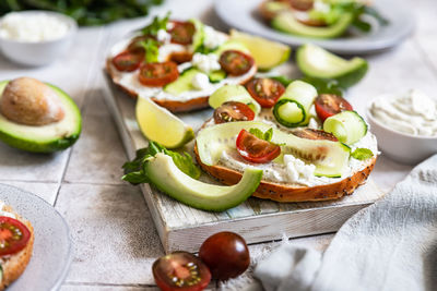 Bagels sandwich with cream cheese, cottage cheese, avocado, tomatoes, cucumbers and salad leaves