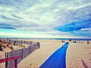 Scenic view of beach against cloudy sky