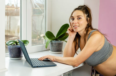 Portrait of young woman using laptop at home