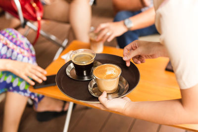 Waitress serving customer a hot coffee at cafe.