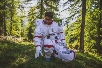 Curious astronaut crouching in forest