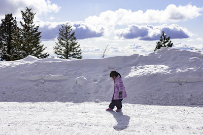 Full length of woman standing on snowcapped mountain against sky