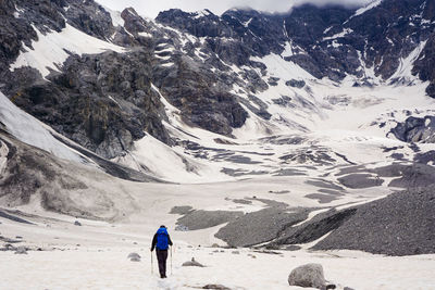 Rear view of person walking on snowcapped mountain