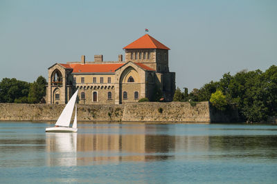 Built structure by lake against clear sky