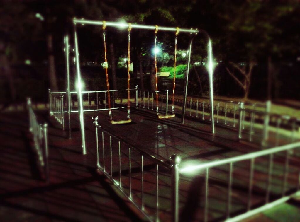 night, illuminated, lighting equipment, railing, street light, bench, fence, built structure, tree, empty, no people, outdoors, metal, architecture, building exterior, focus on foreground, absence, selective focus, light - natural phenomenon, wood - material