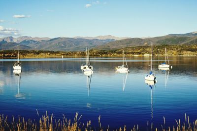 Boats sailing in lake against sky