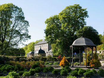 Gazebo amidst trees and pollok house against sky