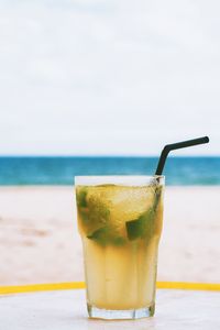 Close-up of drink on table at beach against sky