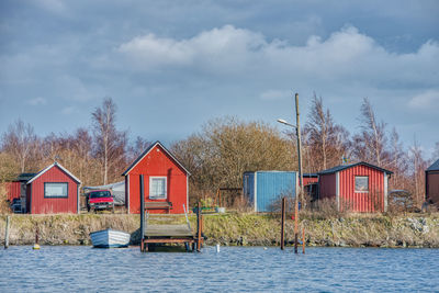 Houses and trees by lake against sky