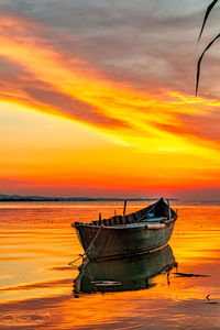 Fishing boat in sea against sunset sky