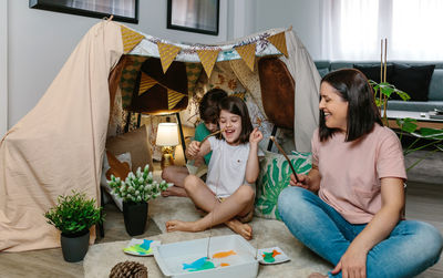 Happy mother and daughter camping at home playing diy fishing game