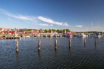 Sailboats in city on sea against sky