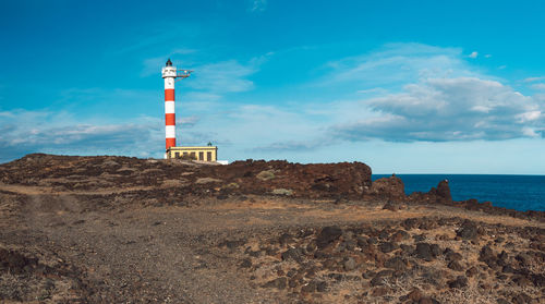 Lighthouse by sea against sky