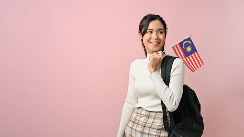Portrait of young woman standing against wall