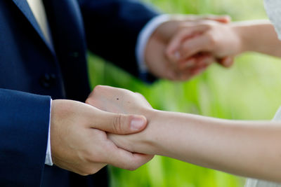 Cropped image of bride and groom holding hands