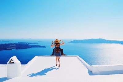 Full length rear view of tourist on building terrace by sea at santorini