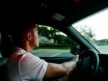 Side view of boy sitting in car