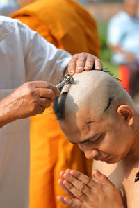 Man cutting hair of monk during ordination