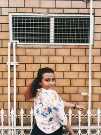 Portrait of smiling woman standing against brick wall