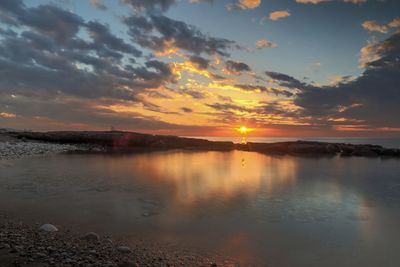 Scenic view of sea against dramatic sky during sunset