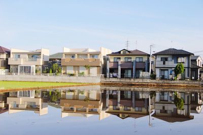 Buildings by lake against sky in city