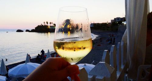 Close-up of hand holding drink against sky