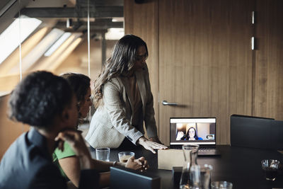 Female entrepreneur on video call through laptop with businesswomen at office