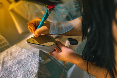 Midsection of woman writing on sandal sole