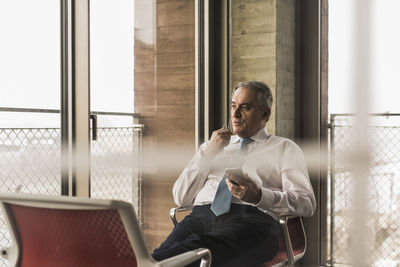 Senior manager in office sitting on chairs with feet up talking on the phone