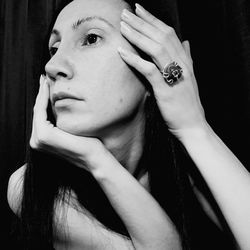 Close-up of woman looking away against black background