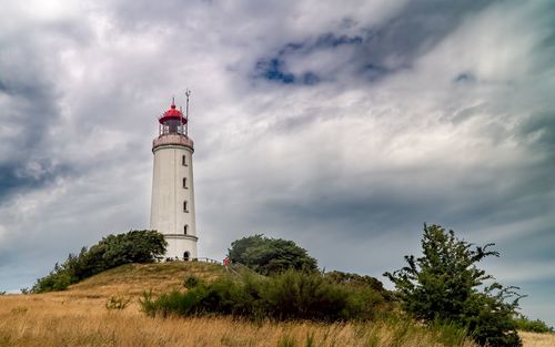 Low angle view of lighthouse by building against sky