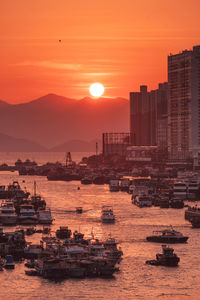 Scenic view of sea by buildings against sky during sunset