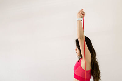 Rear view of woman with arms raised against white background