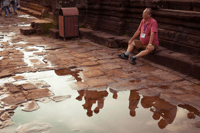 Full length of man sitting by building