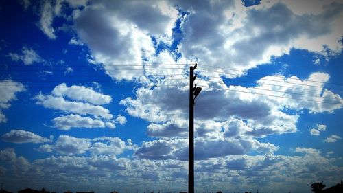 Low angle view of power lines against cloudy sky