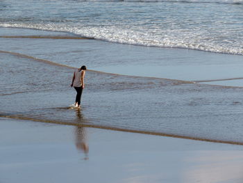 Rear view of woman standing at beach