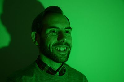 Close-up of smiling man in green light