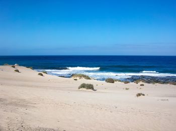 Scenic view of beach against clear blue sky