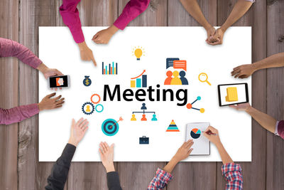 Cropped image of business colleagues by various signs having meeting on conference table in office