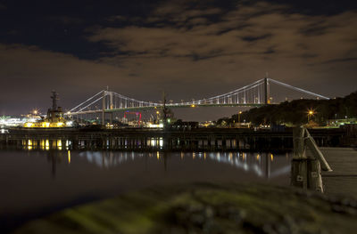 View of suspension bridge over river at night