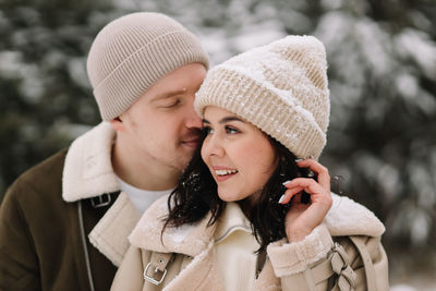 A man and a woman in love walk in a snowy forest among trees in the winter countryside in nature