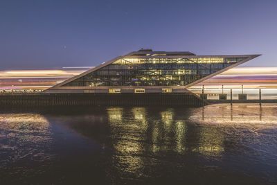 Germany, hamburg, dockland ferry terminal at dawn with light trails of passing ship behind