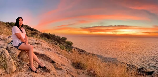 Woman on land against sky during sunset