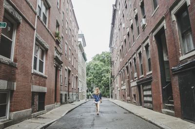 Rear view of woman walking on road amidst buildings